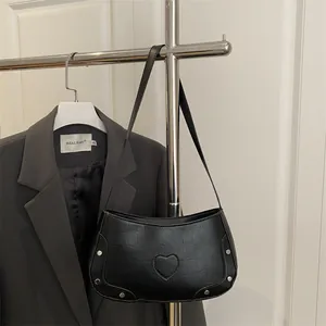 Sac hobo noir chic gaufré crocodile avec patch cœur montré de profil élégamment