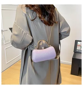 Detailansicht der lila Glitzer-Abendtasche mit Goldgriff auf elegantem grauem Mantel