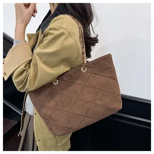 Detail view of brown quilted suede tote bag with golden hardware and chain strap