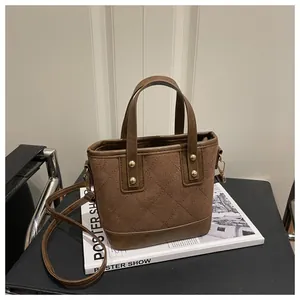 Detailed close-up of brown quilted bucket bag with golden studs and smooth leather handles