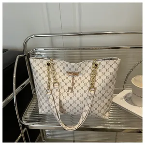 Detail view of large tote bag with geometric print, gold chain strap, and deer charm