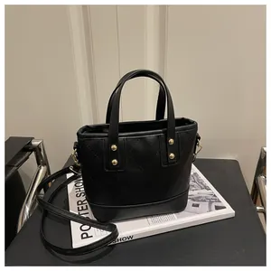 Detail of black quilted tote bag with golden studs and adjustable shoulder strap
