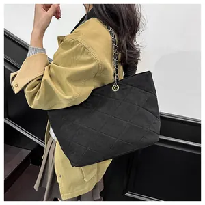 Close-up of black quilted suede shoulder bag with elegant gold-tone chain strap detail