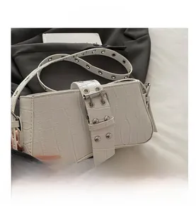Detail view of white crocodile pattern shoulder bag with silver eyelets and metal buckle