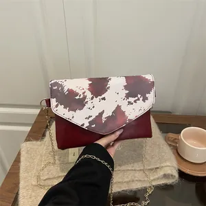 Borsa a tracolla rosso scuro con pattina artistica mostrata in un set elegante