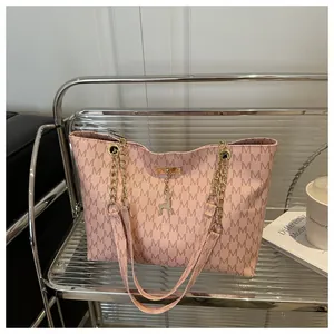Close-up of pink tote bag with M letter print, metal chain strap and deer pendant detail