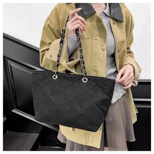 Detail of black quilted suede tote bag with elegant gold and black chain shoulder straps