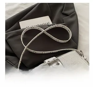 Detail showing white crocodile texture and silver buckle on chic underarm handbag