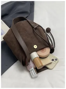 Vue détaillée du sac seau en daim marron montrant la capacité pour maquillage et téléphone