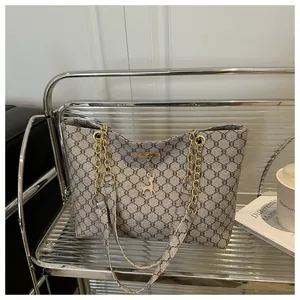Detail of geometric tote bag with gold chain strap and deer charm on a metal shelf
