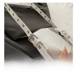 Detailed close-up of white crocodile pattern shoulder bag strap with silver metal eyelets