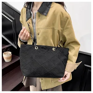 Detail of black quilted suede tote bag featuring elegant gold chain straps for women