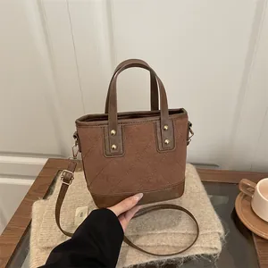 Brown quilted bucket bag with golden studs and crossbody strap for autumn/winter
