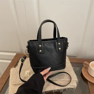 Quilted black leather bucket tote bag with gold hardware and versatile crossbody strap