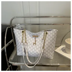 Detail of white tote bag with gray M-pattern print and golden elk metal pendant charm