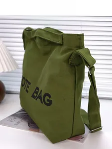 Side view of olive green canvas tote bag with adjustable strap and metal hardware