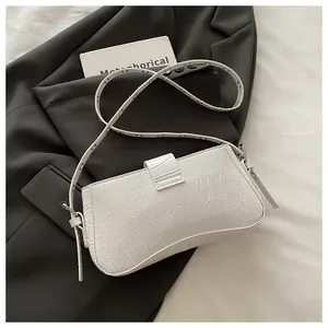 Close-up of white crocodile embossed leather underarm bag with silver eyelet strap
