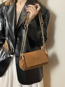 Sac cabas en daim marron avec surpiqûres croisées et chaîne dorée porté par mannequin