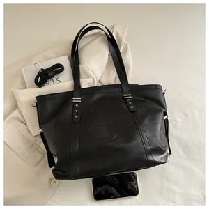 Detail view of black soft leather tote bag with metal star rivets and long strap