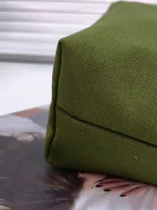 Detailed close-up of green canvas tote bag stitching and sturdy bottom contour