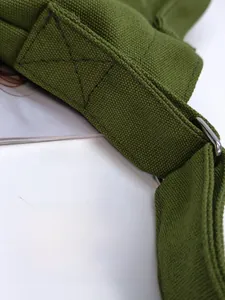 Close-up of reinforced X-shaped stitching on army green canvas shoulder bag strap