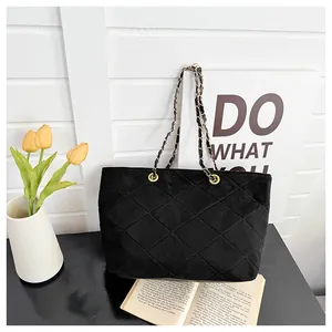 Close-up of black velvet quilted tote bag with golden metal chain on a stylish backdrop