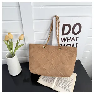 Detail of brown suede tote bag featuring quilted rhombus pattern and gold chain strap