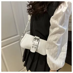 Detail of white crocodile texture underarm bag with silver buckle on a shoulder model