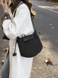 Sac seau chic en daim noir avec patchwork en cuir et breloque boule pour l'automne