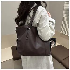Close-up of a dark brown textured leather tote bag with silver star rivets on the shoulder
