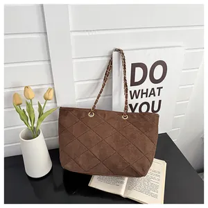 Detail of brown suede tote bag with quilted diamond pattern and gold chain strap