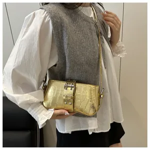 Close-up of golden crocodile embossed underarm bag featuring a large silver buckle strap