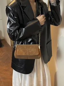 Sac bandoulière en daim marron avec détails de surpiqûres et chaîne dorée sur mannequin