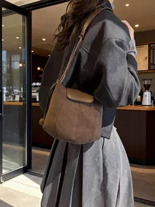 Sac seau vintage en daim marron avec rabat et bandoulière fine pour femme élégante