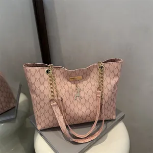 Pink monogram tote bag with gold chain strap and deer pendant on a minimalist background