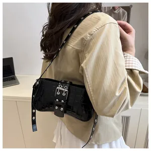 Detail of black croc-embossed underarm bag with metallic buckle and eyelet strap