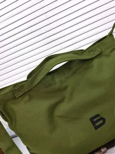Close-up of military green canvas tote bag with reinforced handles and TOTE BA print
