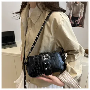Detail of black crocodile pattern shoulder bag with silver eyelet strap and metallic buckle