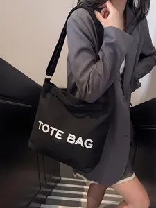 Detail of adjustable shoulder strap and TOTE BAG text on a black canvas crossbody bag
