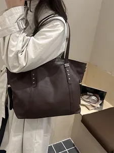Brown leather tote bag with star studs shown on a model in an elegant commute style