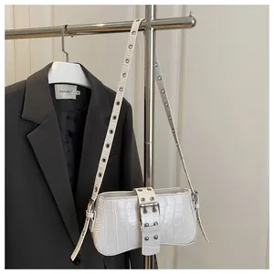 Macro detail of white crocodile pattern shoulder bag with metallic buckle and eyelet strap