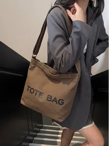 Close-up of a vintage brown canvas tote bag with black lettering and adjustable strap
