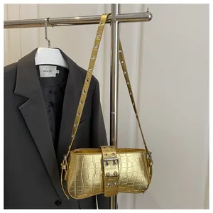 Detail of golden crocodile embossed shoulder bag with metallic grommets on the strap