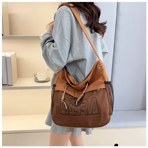Detailed view of brown canvas shoulder bag with WIRA letter design and mesh pockets