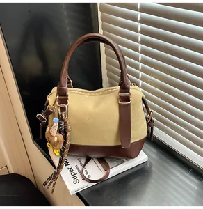 Détail du sac bowling en toile avec garniture en cuir brun, charm ours et gland