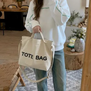 Minimalist beige canvas tote bag with black print and adjustable shoulder strap for women