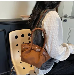 Detail of caramel suede handbag with unique folded closure and buckle strap accents