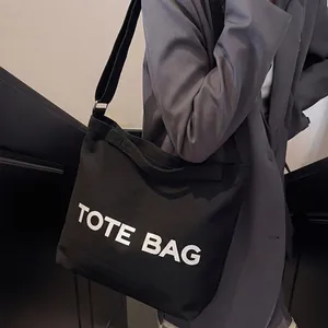 Black canvas tote bag with adjustable strap and TOTE BAG print for daily commute