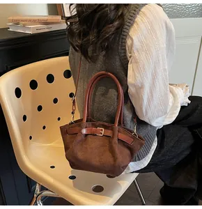 Detail of vintage dark brown suede bucket bag with leather strap and buckle decoration