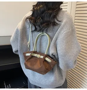 Detail view of the brown suede bucket bag with light green leather buckle and handle